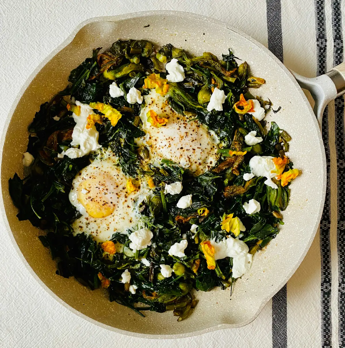 Green shakshuka with eggs and crumbled cheese in a skillet